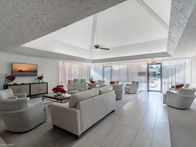 Living area with a tray ceiling, plenty of natural light, a ceiling fan, and a textured wall