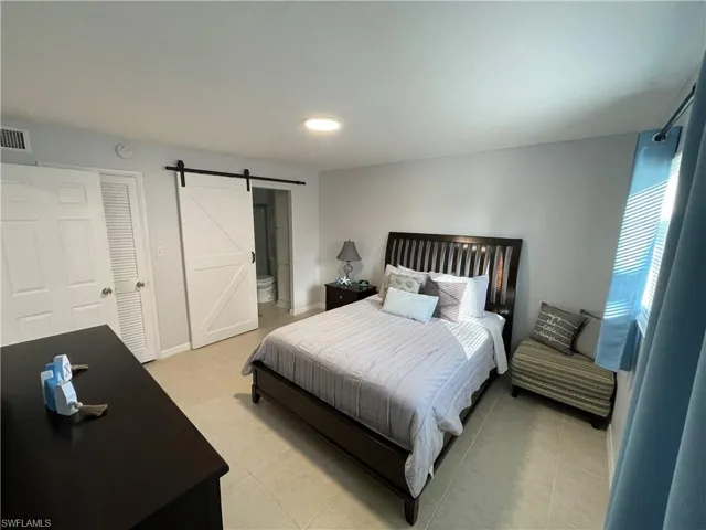 Bedroom with a barn door and connected bathroom