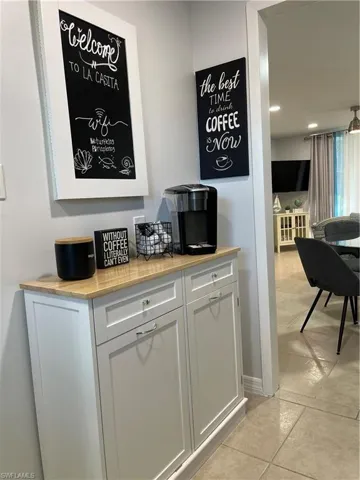 Bar featuring white cabinets, wood counters, recessed lighting, and light tile patterned floors