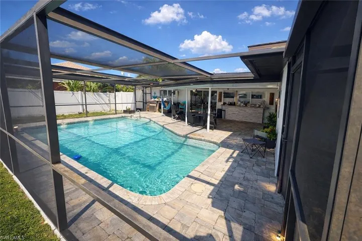View of swimming pool with a lanai, patio surround, a fenced backyard, and a sunroom