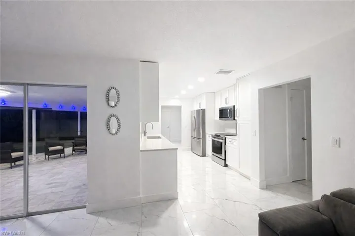 Kitchen with white cabinetry, stainless steel appliances, light stone counters, and recessed lighting