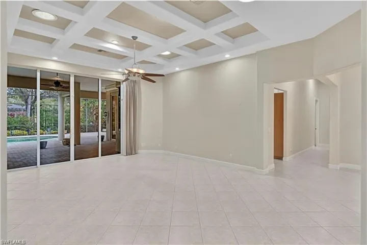 Spare room featuring light tile patterned flooring, ceiling fan, beam ceiling, and coffered ceiling