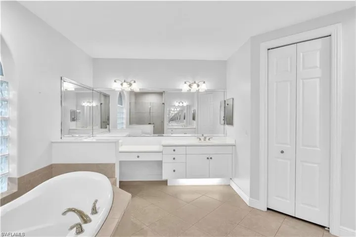 Bathroom featuring a relaxing tiled tub, double vanity, and tile patterned flooring
