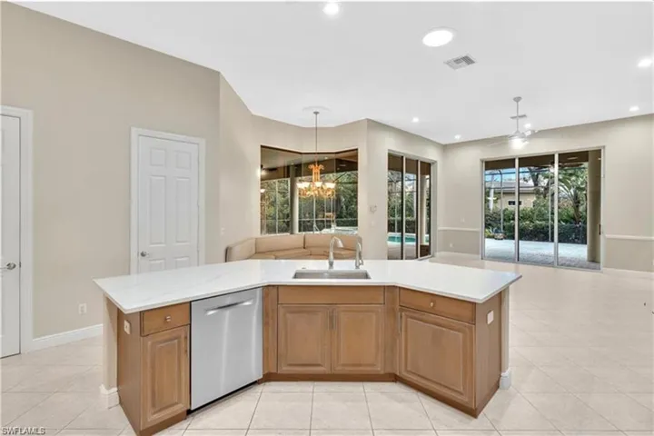 Kitchen featuring sink, a kitchen island with sink, dishwasher, and light tile patterned floors