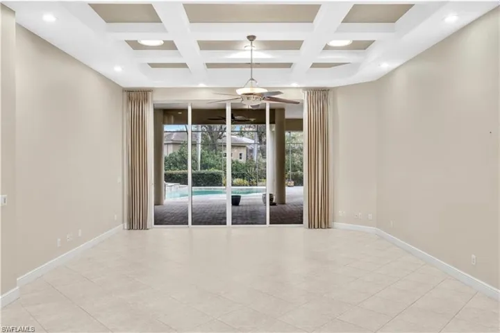 Tiled great room with beam ceiling, coffered ceiling, and ceiling fan