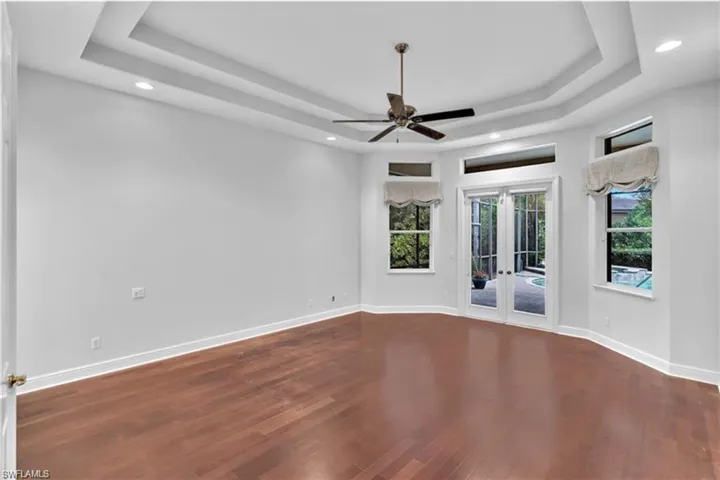 Empty room featuring wood-type flooring, french doors, and a tray ceiling