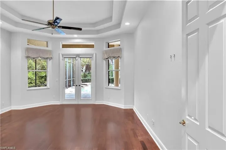 Spare room featuring french doors, ceiling fan, wood-type flooring, and a raised ceiling