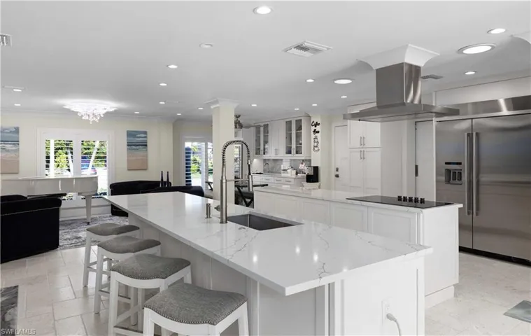 Kitchen featuring black electric cooktop, island range hood, high end refrigerator, a sink, and a large island