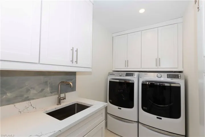 Washroom with cabinet space, washing machine and dryer, a sink, and recessed lighting