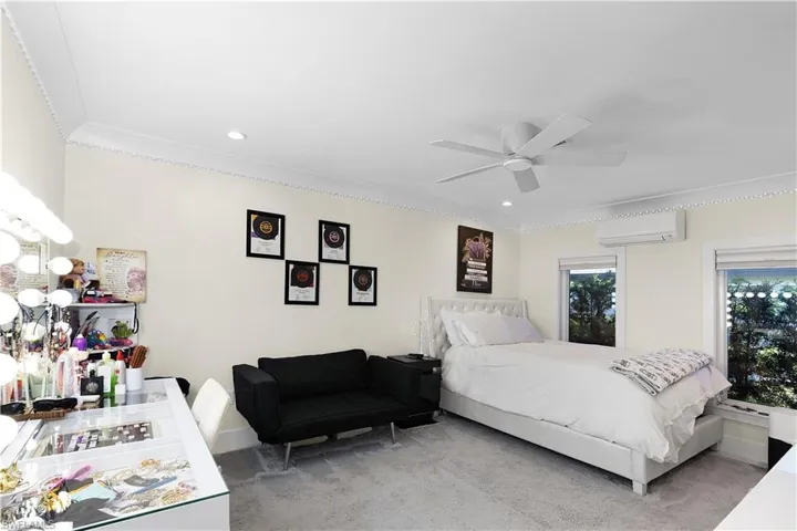 Bedroom with light carpet, an AC wall unit, recessed lighting, and crown molding