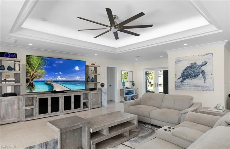Living room featuring a ceiling fan, a tray ceiling, crown molding, and recessed lighting
