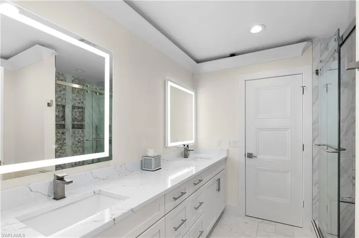 Full bathroom with marble finish floor, a sink, a marble finish shower, and double vanity