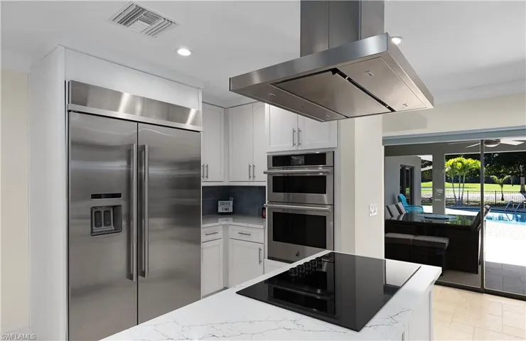 Kitchen featuring visible vents, stainless steel appliances, light stone counters, and exhaust hood