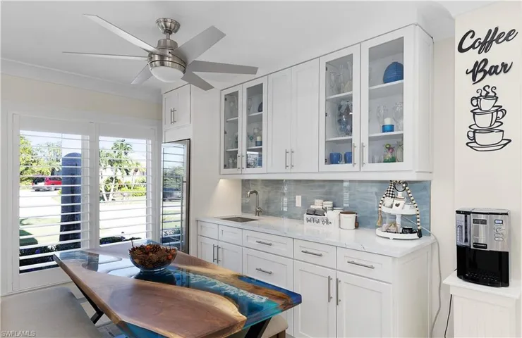 Kitchen with a sink, white cabinetry, light stone countertops, tasteful backsplash, and glass insert cabinets