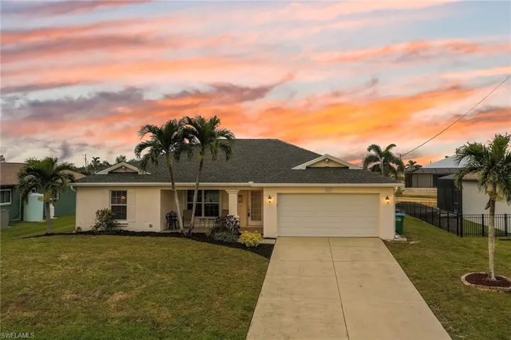 View of front of home with a yard and a garage