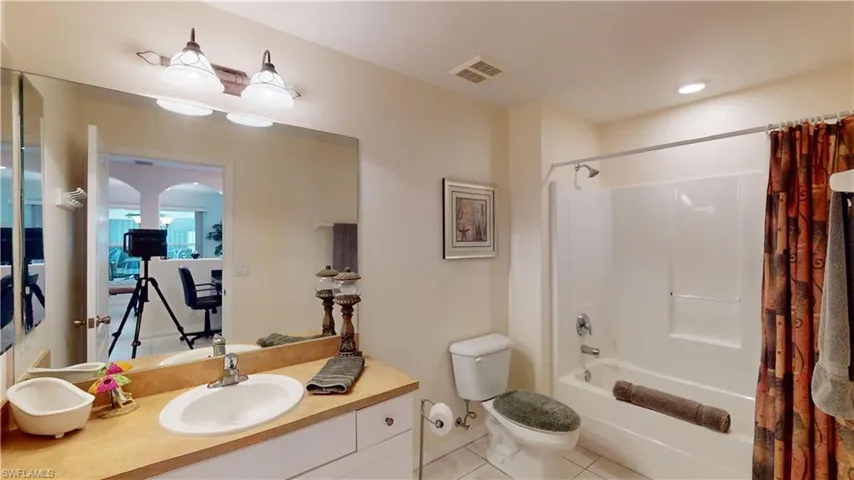 Full bathroom featuring toilet, vanity, tile patterned floors, and shower / bath combo with shower curtain
