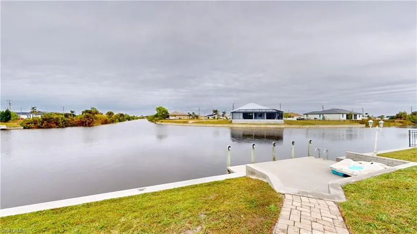 View of dock with a lawn and a water view