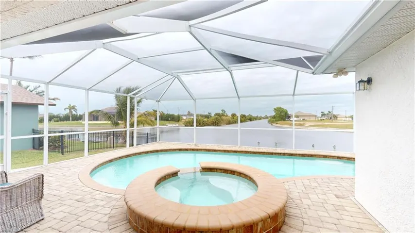 View of swimming pool featuring glass enclosure, an in ground hot tub, and a patio