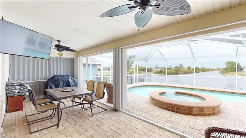 Sunroom / solarium with ceiling fan and a swimming pool with hot tub
