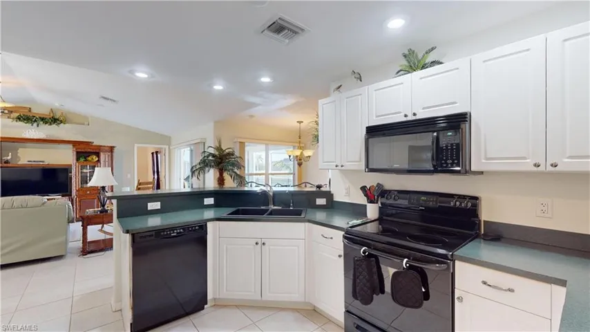 Kitchen featuring white cabinets, sink, kitchen peninsula, and black appliances