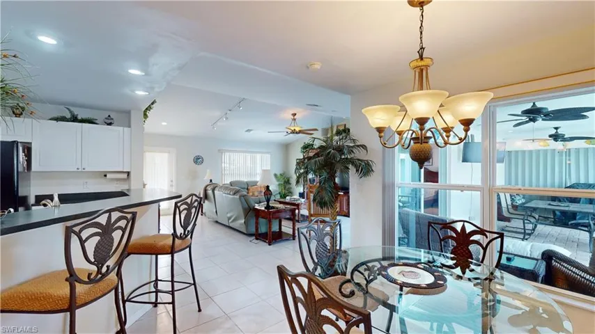 Tiled dining room with rail lighting and ceiling fan with notable chandelier