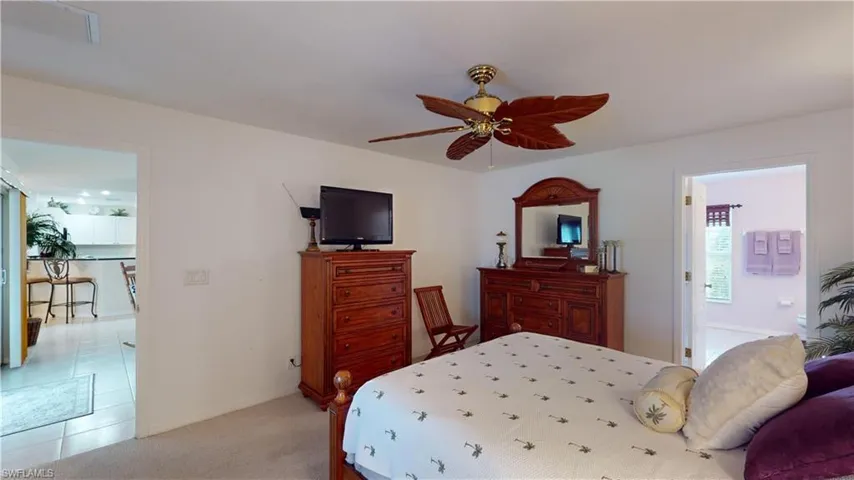 Bedroom featuring connected bathroom, light colored carpet, and ceiling fan