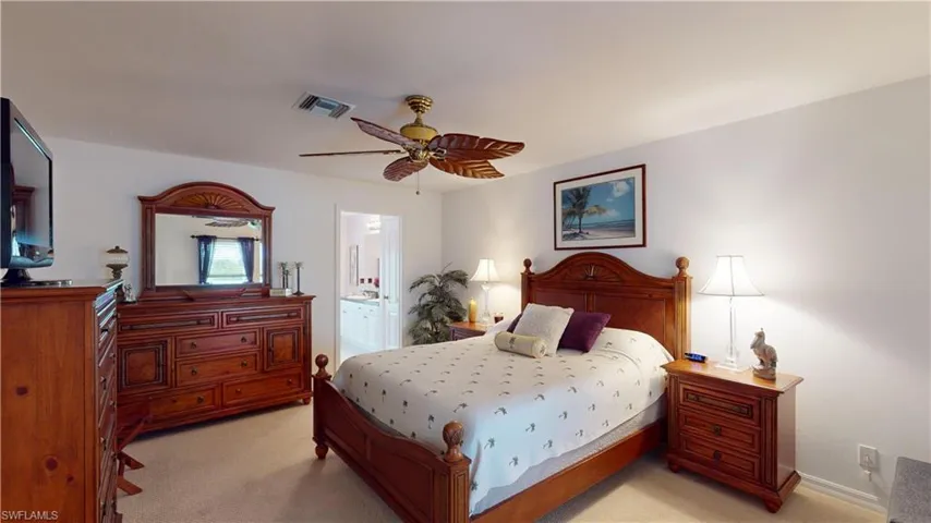 Bedroom with ensuite bath, ceiling fan, and light carpet