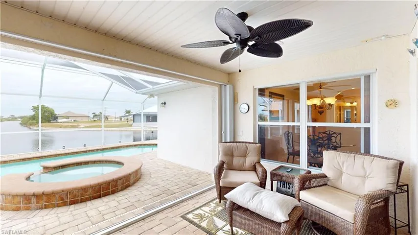 Sunroom / solarium featuring a pool with hot tub, ceiling fan, and a water view