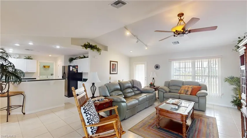 Living room with ceiling fan, lofted ceiling, and light tile patterned flooring