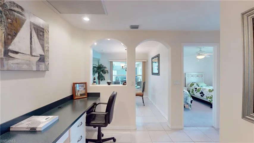 Tiled home office with ceiling fan with notable chandelier and built in desk