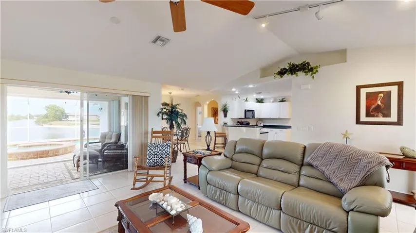 Tiled living room with ceiling fan, lofted ceiling, and track lighting