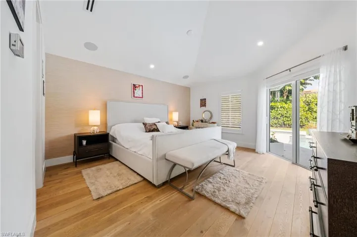 Bedroom featuring light hardwood / wood-style flooring, access to exterior, and lofted ceiling