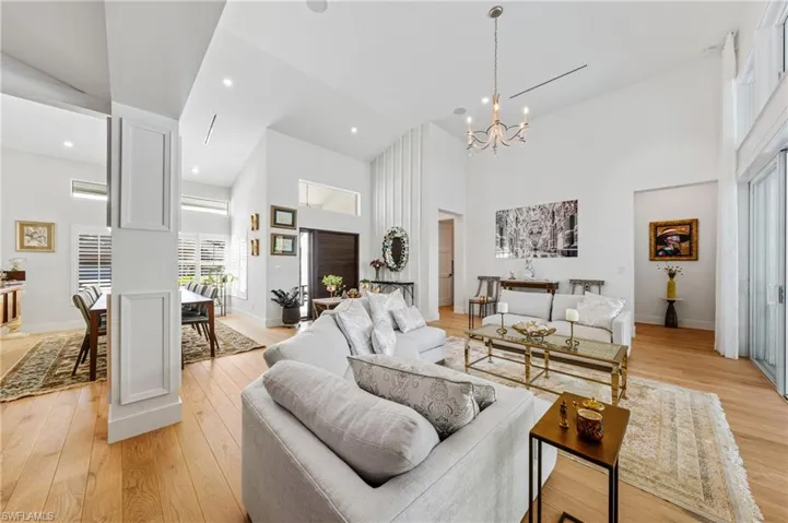 Living room featuring a towering ceiling, an inviting chandelier, and light hardwood / wood-style floors