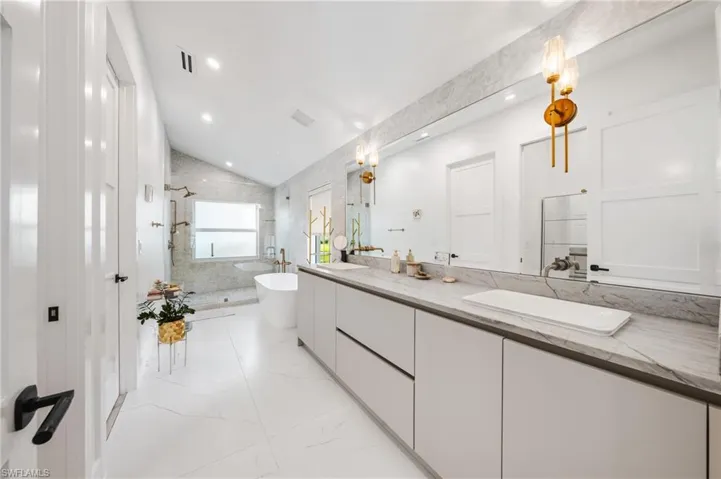 Bathroom featuring shower with separate bathtub, vaulted ceiling, and vanity