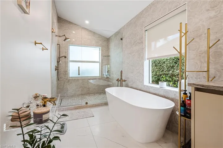 Bathroom with lofted ceiling, plus walk in shower, and a healthy amount of sunlight