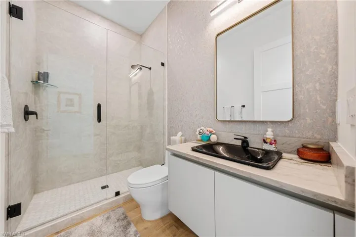 Bathroom featuring hardwood / wood-style flooring, toilet, vanity, and walk in shower