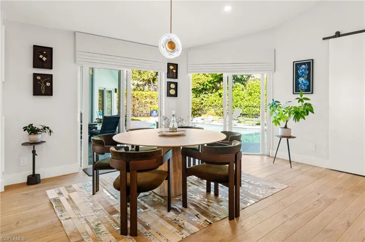 Dining space with light hardwood / wood-style flooring, vaulted ceiling, and a barn door