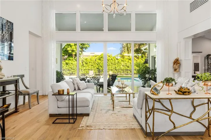 Living room featuring light wood-type flooring, a high ceiling, and an inviting chandelier
