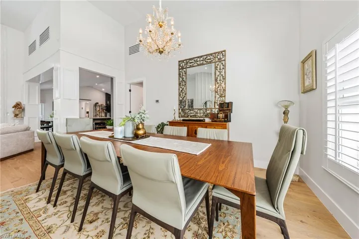 Dining room featuring a notable chandelier, light hardwood / wood-style flooring, and a high ceiling