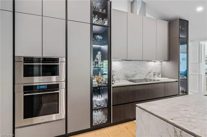 Kitchen with light hardwood / wood-style flooring, stainless steel double oven, black electric stovetop, and decorative backsplash