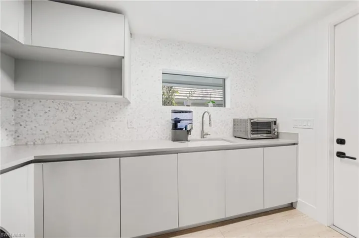 Kitchen featuring sink, white cabinets, and tasteful backsplash