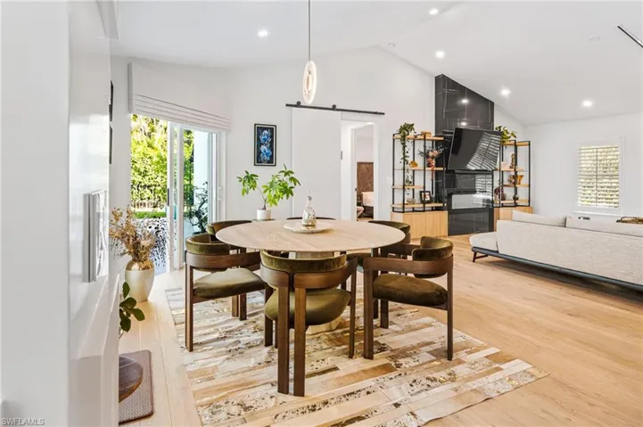 Dining area featuring high vaulted ceiling, wood-type flooring, and a barn door
