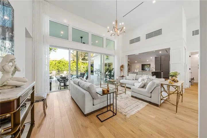 Living room featuring light wood-type flooring, a high ceiling, and an inviting chandelier