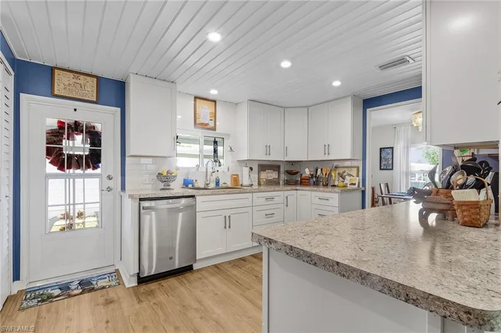 Kitchen featuring plenty of natural light, white cabinetry, light wood-type flooring, and stainless steel dishwasher