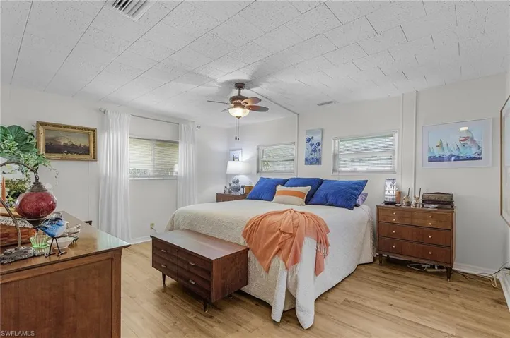 Bedroom with light hardwood / wood-style floors, multiple windows, and ceiling fan