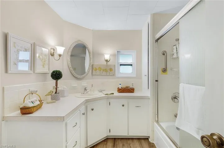 Bathroom with vanity, combined bath / shower with glass door, decorative backsplash, and hardwood / wood-style floors