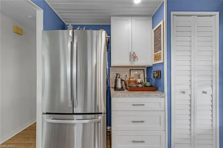 Kitchen with white cabinets, stainless steel fridge, decorative backsplash, and hardwood / wood-style floors
