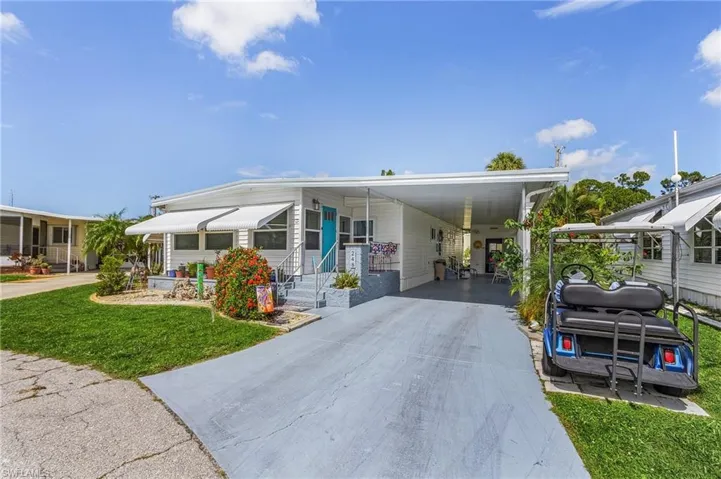 Manufactured / mobile home featuring a carport and a front yard