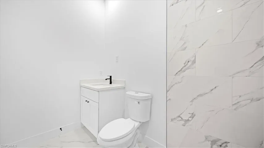 Full bath with vanity, light marble finish floors, and a marble finish shower