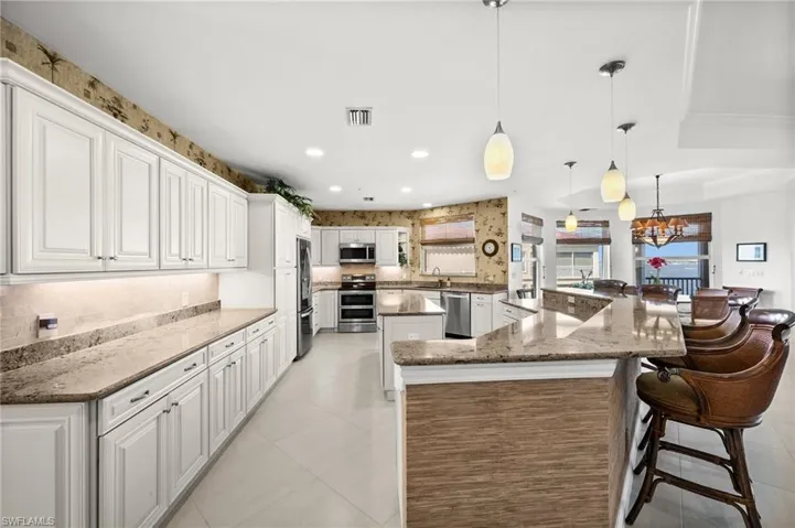 This open gourmet kitchen is an invitation to sit at the countertop, boasting super comfortable elevated bar chairs. Enjoy the modern decorative light fixtures!
